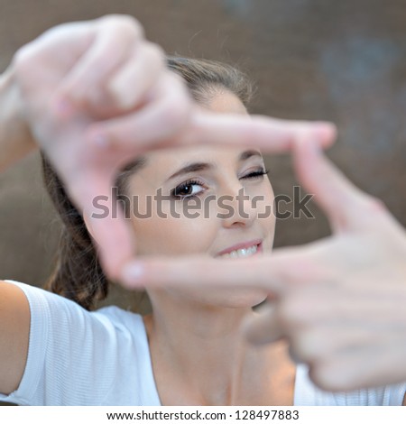 Portrait of young woman creates a frame with her hands