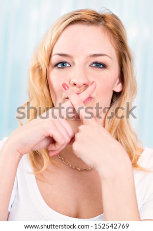 Close up portrait of young woman with finger on lips