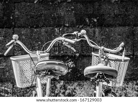 two classic bicycle in front of sand stone wall in black and white