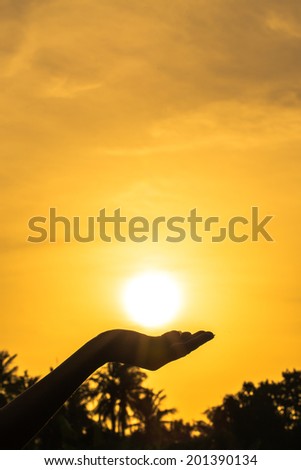 hands holding the sun at sunset
