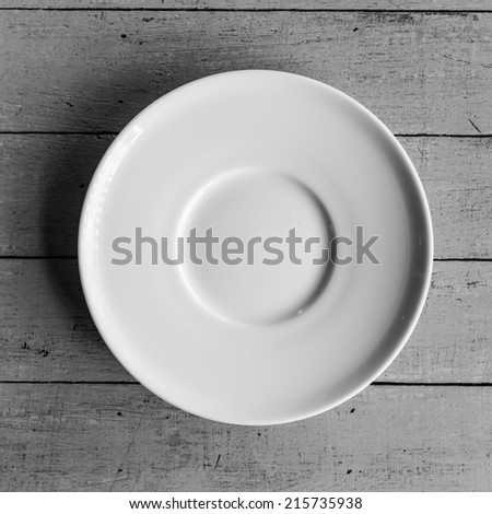 White dish on wood table. Black and white photo.