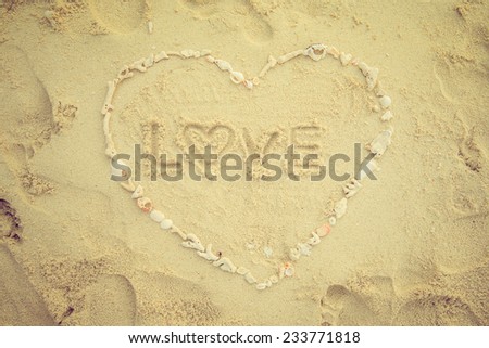concept LOVE in heart made from seashell on sand beach. Vintage filter.