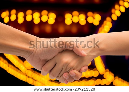 Business man and woman make hand shake with abstract bokeh theater light