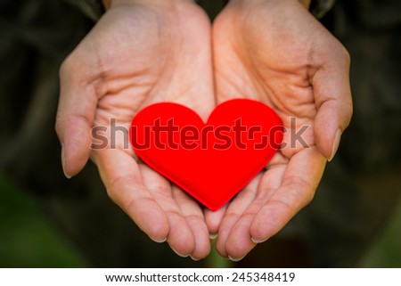 female hand holding fabric red valentine heart.Valentines Day background.
