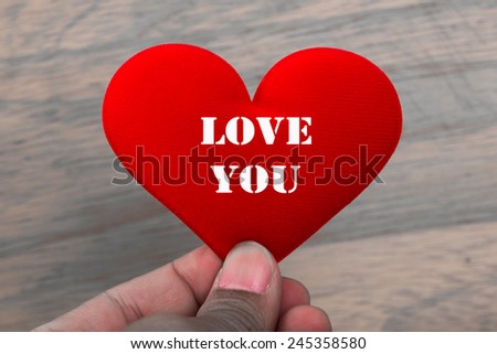 Male hand hold fabric red heart with word 