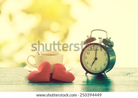 Concept a cup of hot espresso with two valentine hearts and alarm clock. Vintage filter. Valentines Day background.