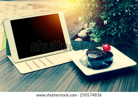 Concept heart shape chocolate on table with computer tablet PC in cafe. Vintage style