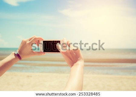 Woman using smart phone take a photo (selfie) on the beach in Thailand. Vintage style.