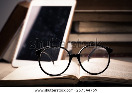 Concept book and tablet PC and eyeglasses on table.
