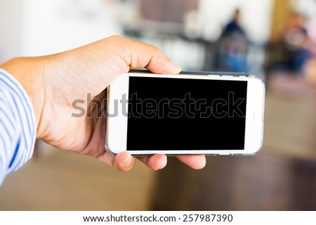 Hand hold smartphone with bokeh coffee restaurant background.