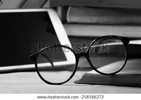 Concept book and tablet PC and eyeglasses on table.