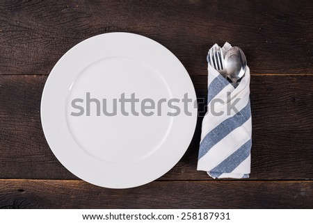 Top view empty plate on dinner table with fork and spoon.