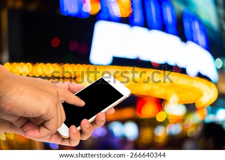 Buying ticket online concept. Using smartphone buying ticket with boken theater marquee lights background.