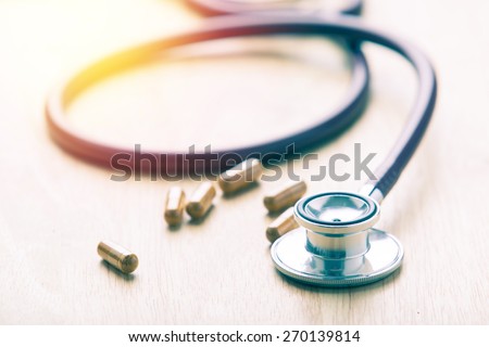 Medical concept.herb capsule and stethoscope background. Vintage filter.
