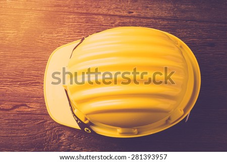 Yellow Safety Helmet Hat with SAFETY FIRST word tag on Wood background. Vintage filter
