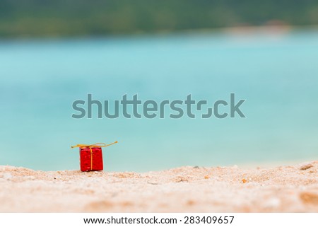 Christmas gift box on beautiful sand beach.