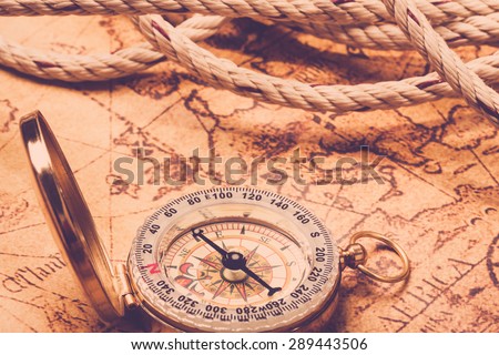 Old vintage compass on vintage map and rope. Vintage filter.