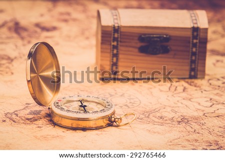 compass lying on vintage map with treasure chest. Vintage filter.