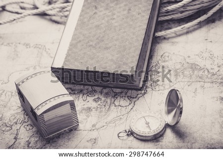 Compass and old book with treasure chase on vintage map. Retro filter