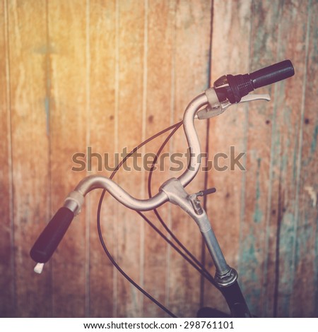 Bicycle handle bar on wood wall background. Vintage filter