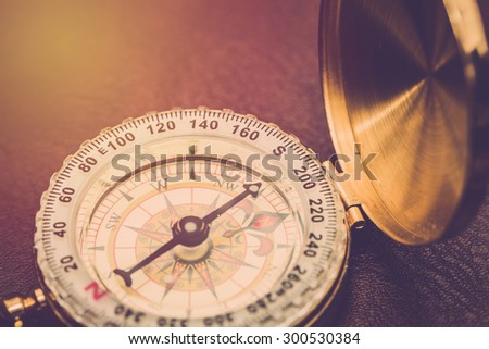 Compass on leather background close up. Vintage filter.