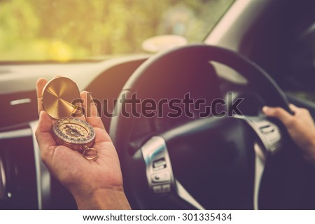 Woman driving car and using compass to navigate. Vintage filter.