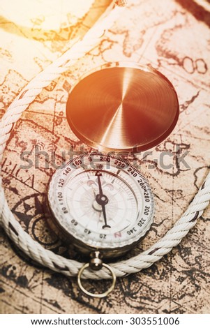 Compass on vintage map with rope. Vintage filter.