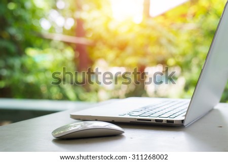 Computer laptop on table in garden. Vintage filter