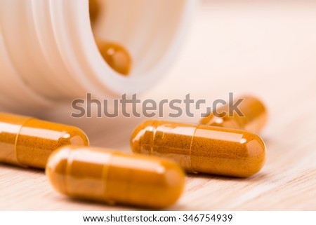 Medical herbal capsule on wood board. Selective focus.