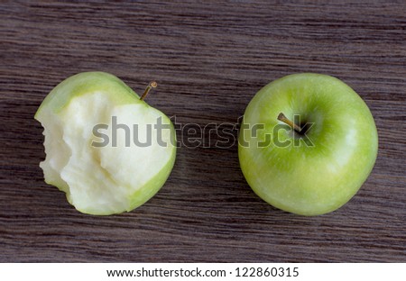 Green Apple and Bitten green Apple, on a wooden board