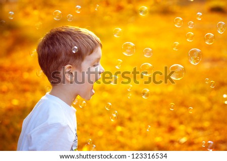 beautiful little boy catches his mouth soap bubbles, closeup portrait