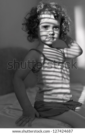 portrait of a beautiful little girl with shadows on the face, black and white shot
