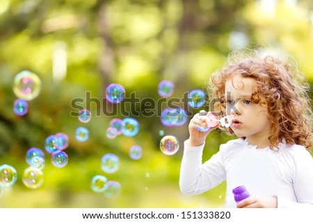 A Little Girl Blowing Soap Bubbles, Closeup Portrait Beautiful Curly Baby.