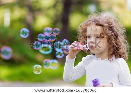 A Little Girl Blowing Soap Bubbles, Closeup Portrait Beautiful Curly Bab