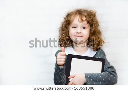 Curly smiling girl with the tablet PC on a light background.