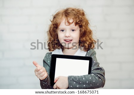 Curly smiling girl with the tablet PC on a light background.