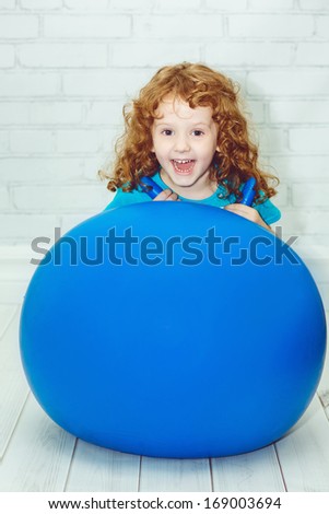 Happy girl doing gymnastics on blue ball.
