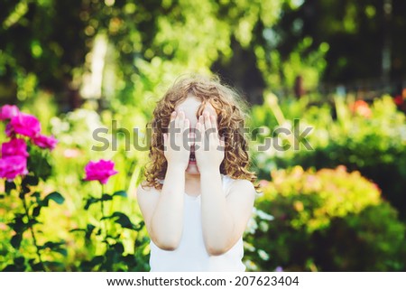 Little girl closed face with her hands, weeping, or playing hide and seek.