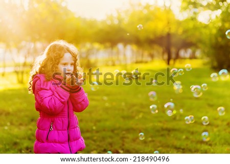 A little girl blowing soap bubbles. Instagram filter.