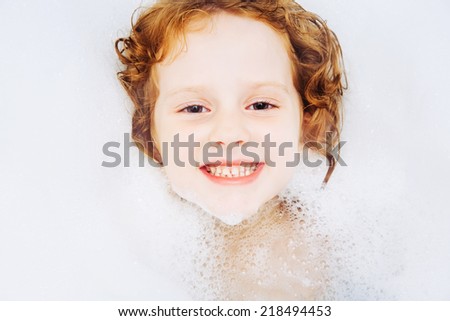Happy little girl surrounded soap suds.