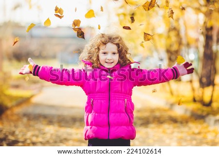 Happy little girl throws the autumn leaves in the air. Instagram filter.