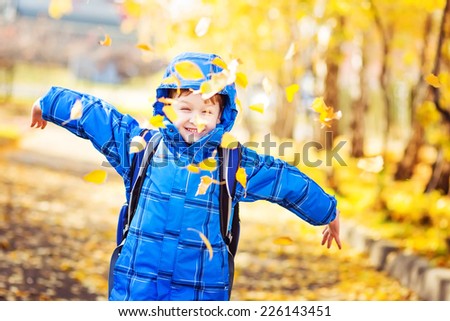 Happy schoolboy throws the autumn leaves in the air. Instagram filter.