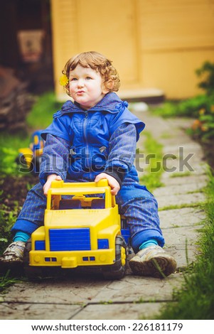 A child plays a toy car on the grass.