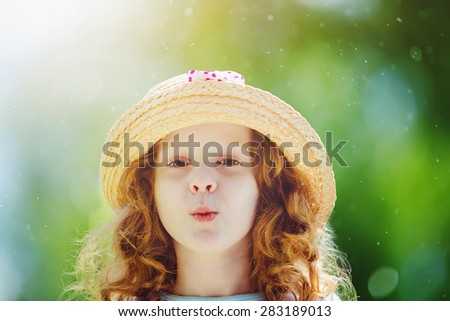 Funny little girl in a straw hat, shaped his lips for a kiss.