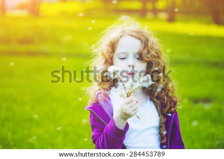 Child with white dandelion in your hand. Background toning instagram filter.
