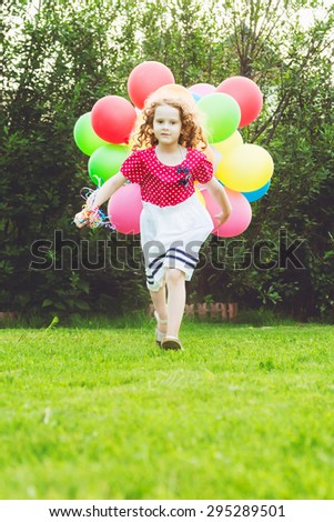 Little curly girl running with colored balloons. Happy childhood concept. Background toned in instagram filter.