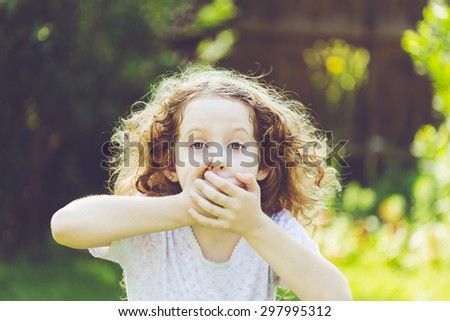 Little girl covering her mouth with her hands. Surprised or scared.