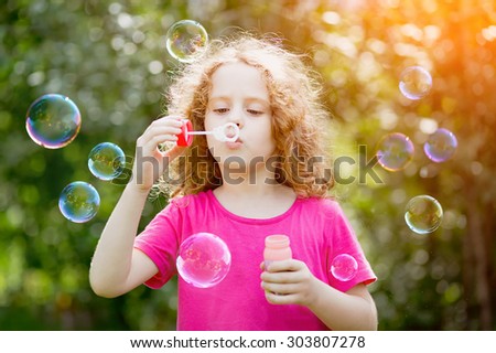 Girl blowing soap bubbles in sunset light, toning at instagram filter.