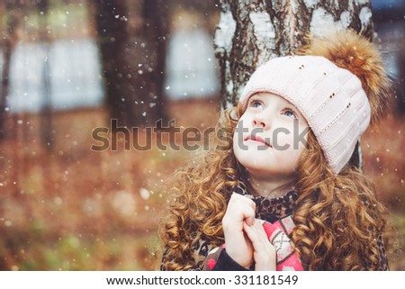 Praying little girl looking up with hope for peace. Happy childhood and world peace concept.