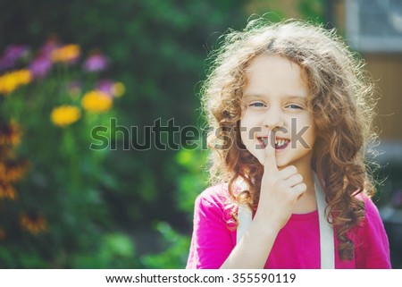little girl putting finger up to lips and ask silence. Toning photo.